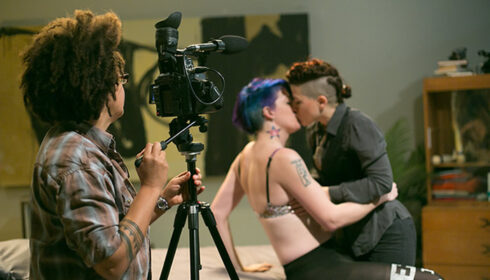 Shine Louise Houston films two queer performers making out on a bed, for the Crash Pad Series.