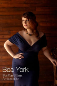 Redhead BBW Bea Yorke poses in a pin-up wiggle dress and a hand on her hip, as a feminist porn ambassador for ForPlay Films